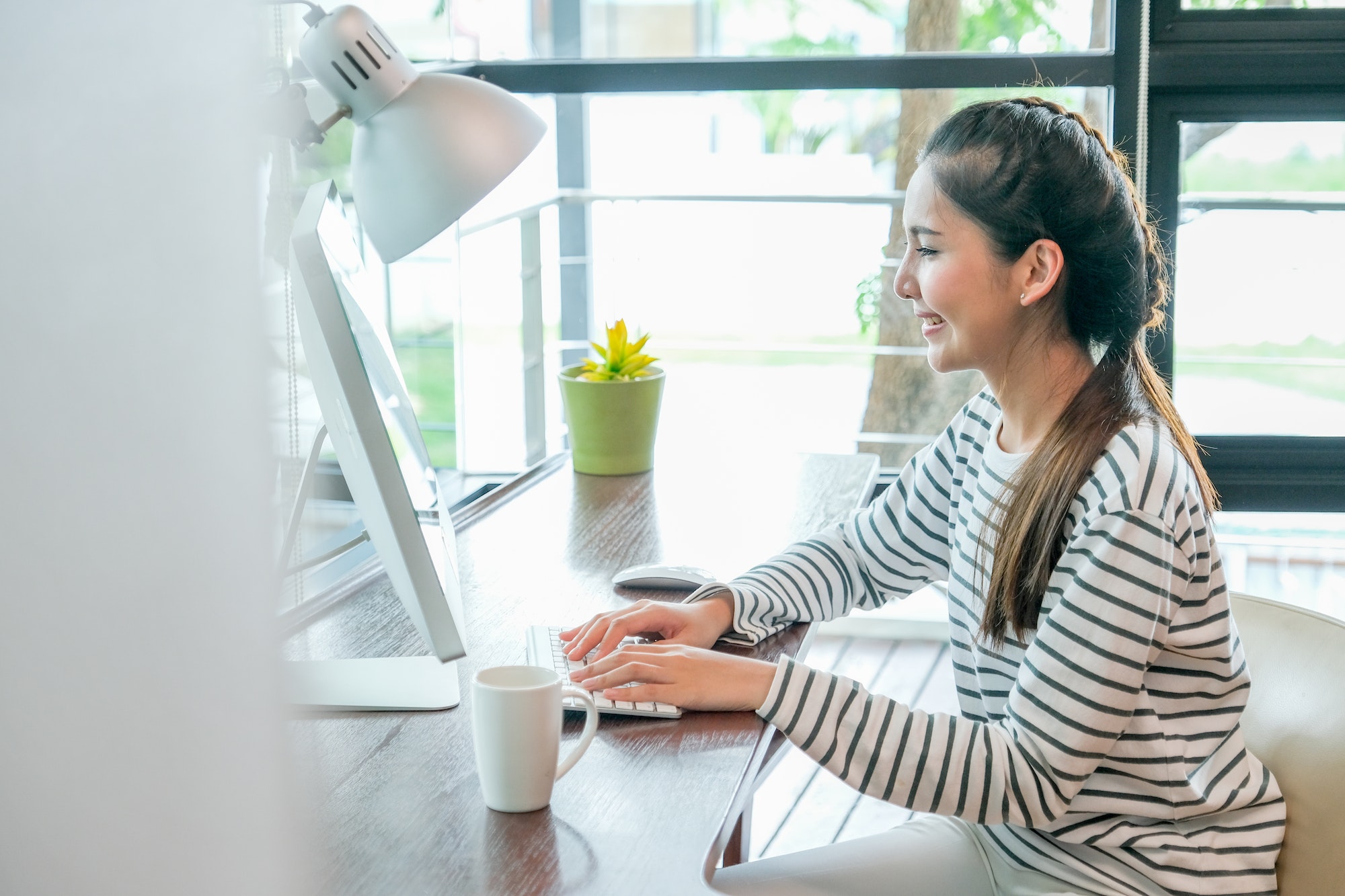 Asian woman look happy by smiling during work with computer in the room with day light