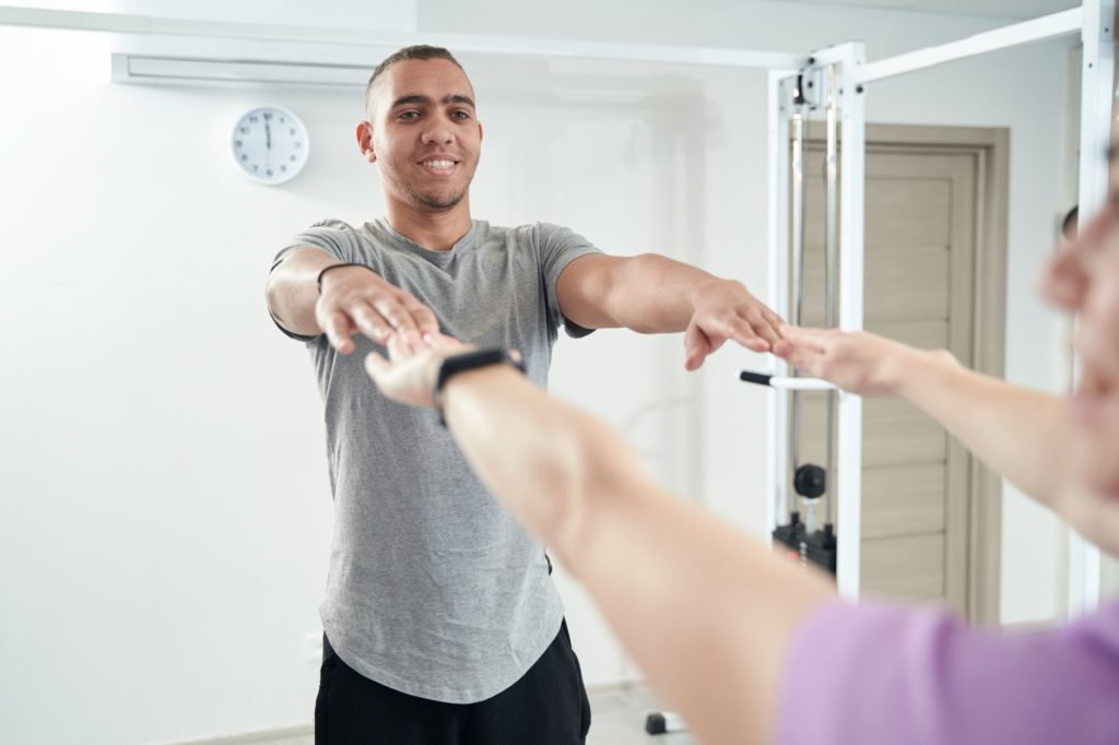 Cheerful man doing physiotherapy exercise in clinic